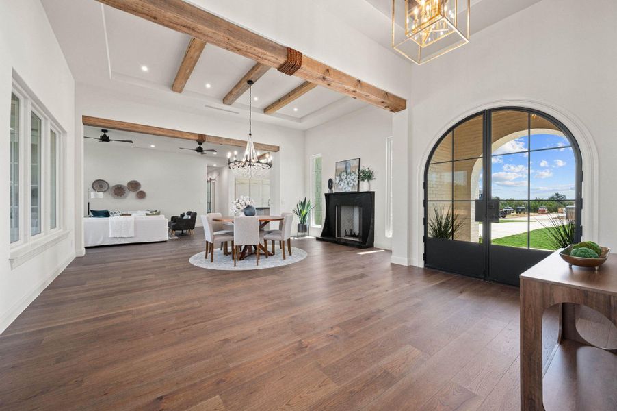 Foyer featuring a chandelier, beam ceiling, wood-style floors, ceiling fan, and a towering ceiling
