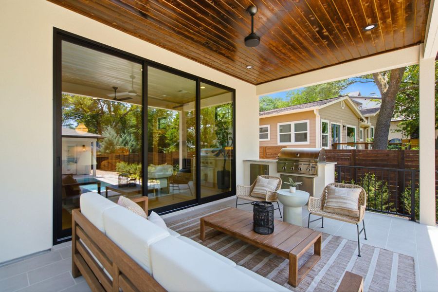 Rich wood plank ceilings and modern sliding glass doors define this sheltered outdoor patio.