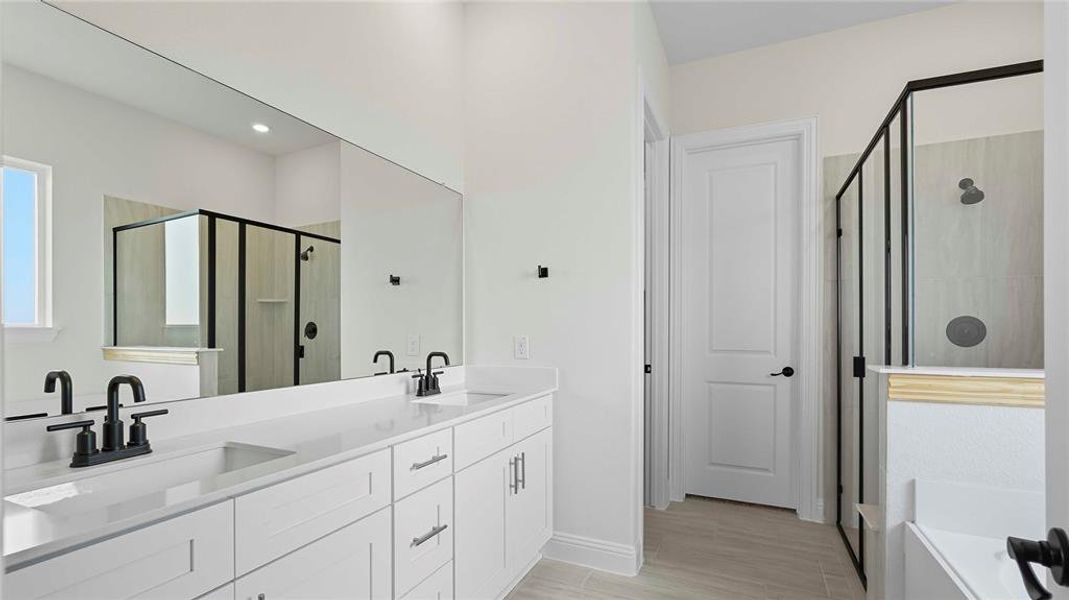 Full bath featuring double vanity, a stall shower, a bath, and light wood finished floors