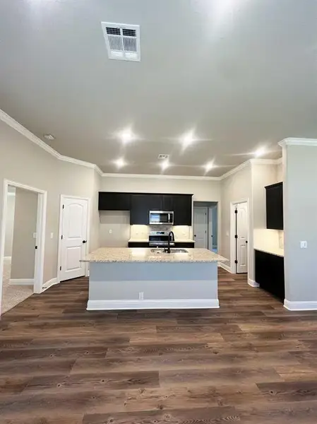 Kitchen featuring stainless steel appliances, visible vents, dark cabinetry, a sink, and crown molding