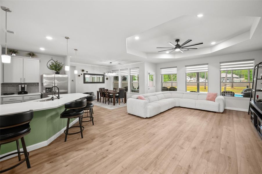 Spacious open-concept living, dining, and kitchen area with numerous windows overlooking the backyard pool.