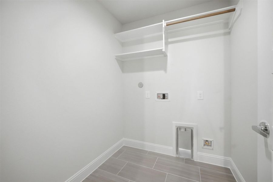 Effortlessly tackle laundry day in this bright and functional laundry room, featuring ample shelving and modern utility hookups.