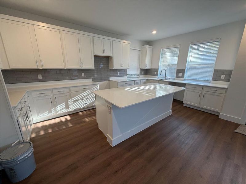 Kitchen featuring tasteful backsplash, white cabinets, dark wood-style flooring, a center island, and recessed lighting