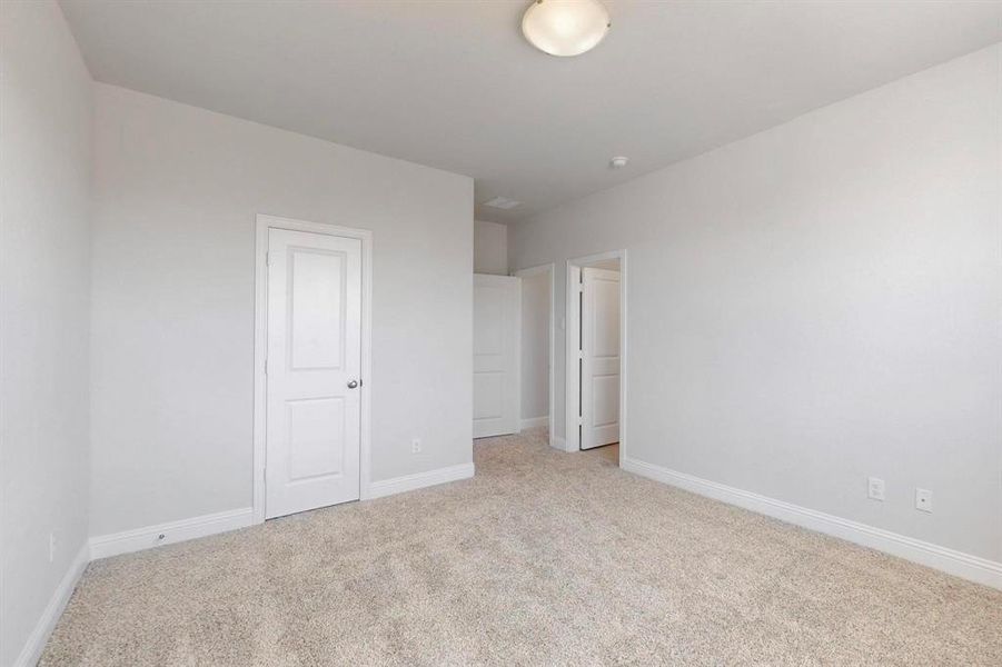 Unfurnished bedroom with light carpet and baseboards