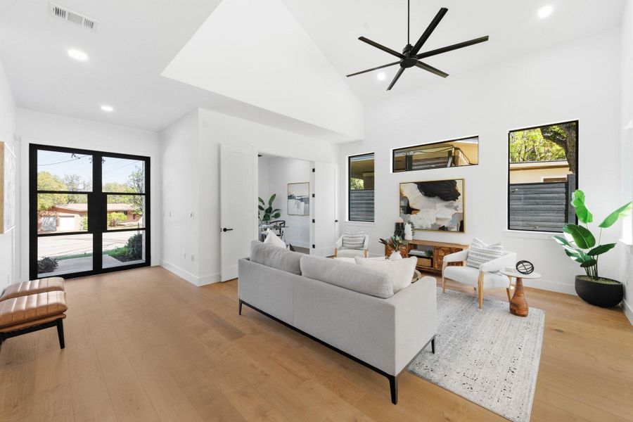 Living room with high vaulted ceiling, recessed lighting, light wood-type a ceiling fan opens to kitchen and dining for ease to entertain Living room with high vaulted ceiling, recessed lighting, light wood-type a ceiling fan opens to kitchen and dining for ease to entertain