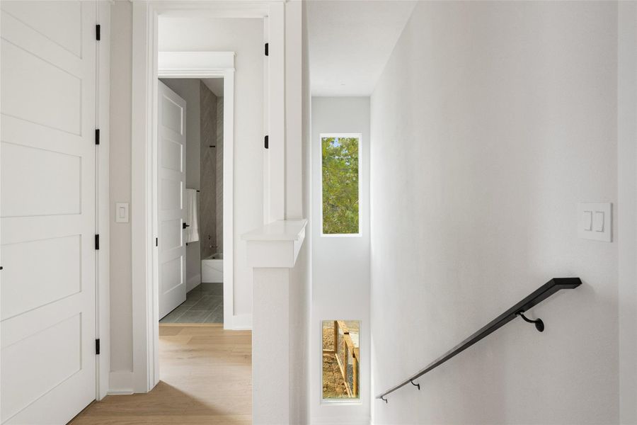Corridor with light wood-style floors and an upstairs landing Corridor with light wood-style floors and an upstairs landing