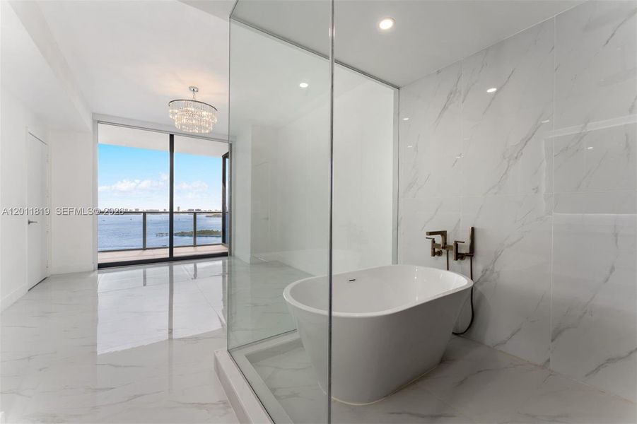 Spa-inspired primary bathroom featuring dual vanities, a deep soaking tub, a frameless glass rainfall shower, and designer porcelain tile throughout.
