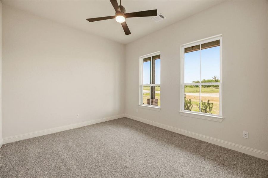 Carpeted spare room featuring baseboards and ceiling fan
