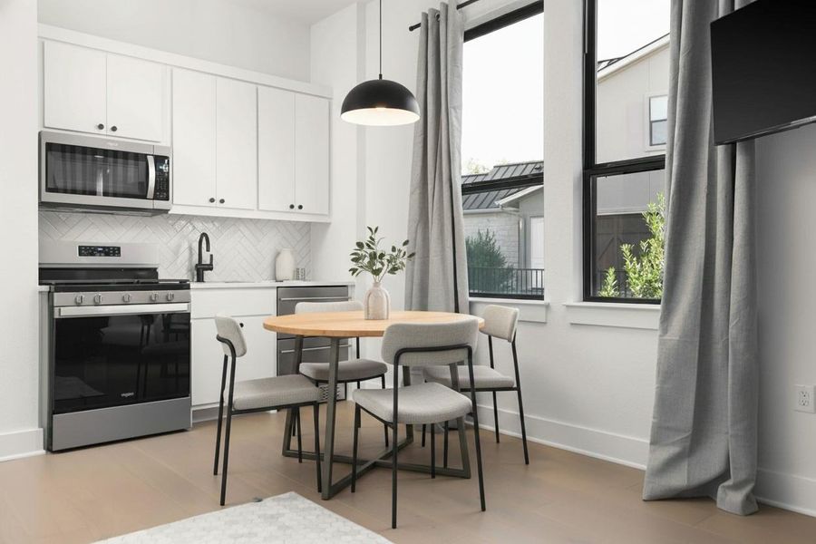 Efficient kitchen space featuring white cabinetry, stainless steel appliances, and a herringbone tile backsplash