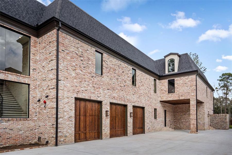 A long motor court leads to a three-bay attached garage with Liftmaster doors, storage cabinets and 220-volt outlets for EV charging and room for 3 car lifts.