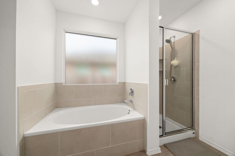 A well-appointed bathroom features a corner soaking tub and a separate glass-enclosed shower.