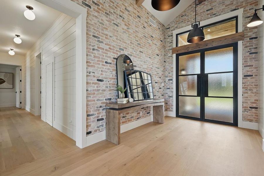 Unfurnished living room with wood finished floors, brick wall, and high vaulted ceiling Unfurnished living room with wood finished floors, brick wall, and high vaulted ceiling