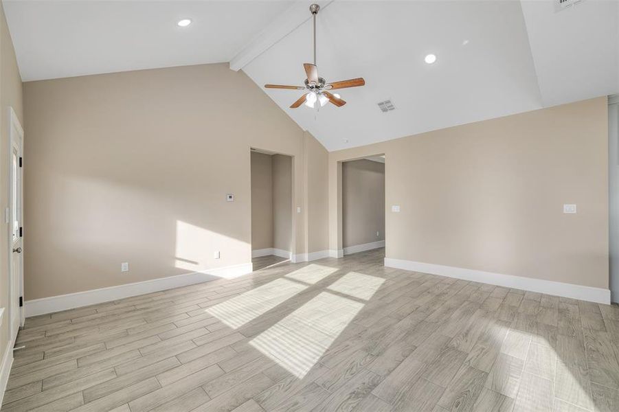 Spare room with beamed ceiling, ceiling fan, high vaulted ceiling, and light hardwood / wood-style flooring