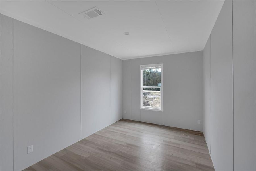 Spare room with a decorative wall and light wood-type flooring