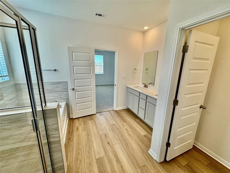 Full bathroom with double vanity, a garden tub, light wood-style flooring, and a shower stall Full bathroom with double vanity, a garden tub, light wood-style flooring, and a shower stall