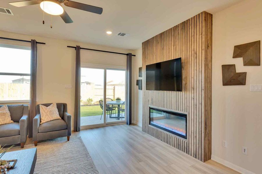 A well-lit living area offers contemporary flooring and a striking fireplace feature wall.