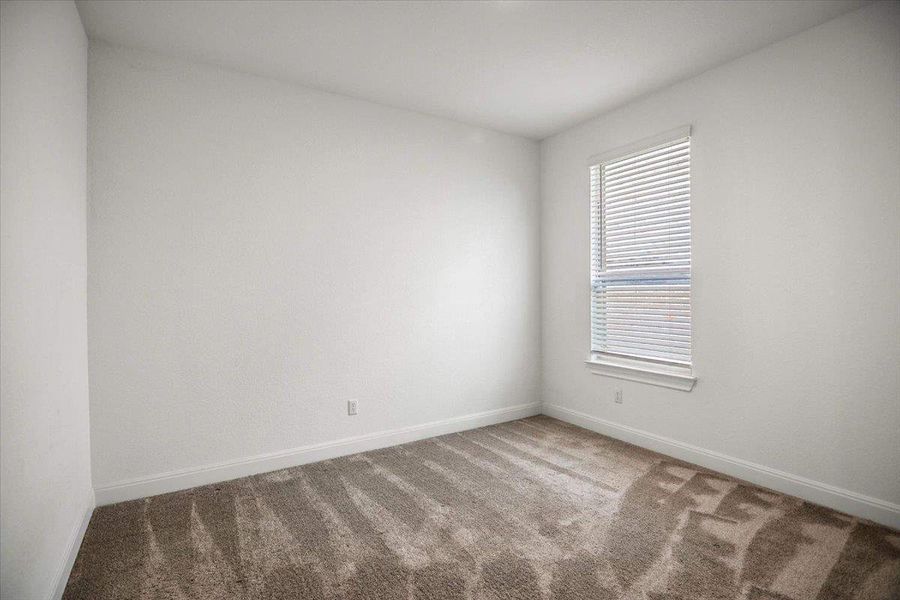 A well-lit room awaits your personal touch with soft, patterned carpeting underfoot.