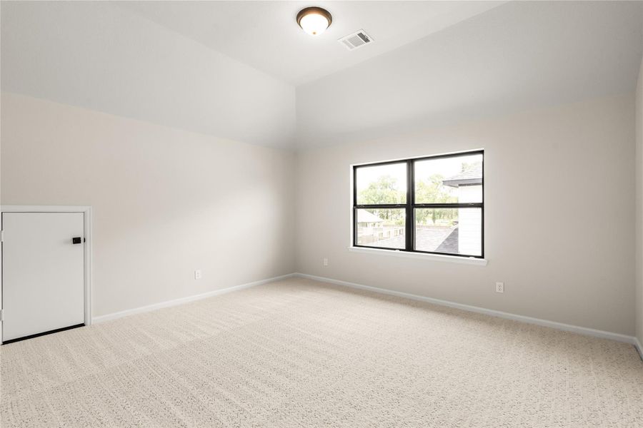 Spacious, light-filled room with plush carpeting, high ceilings, and a large window.