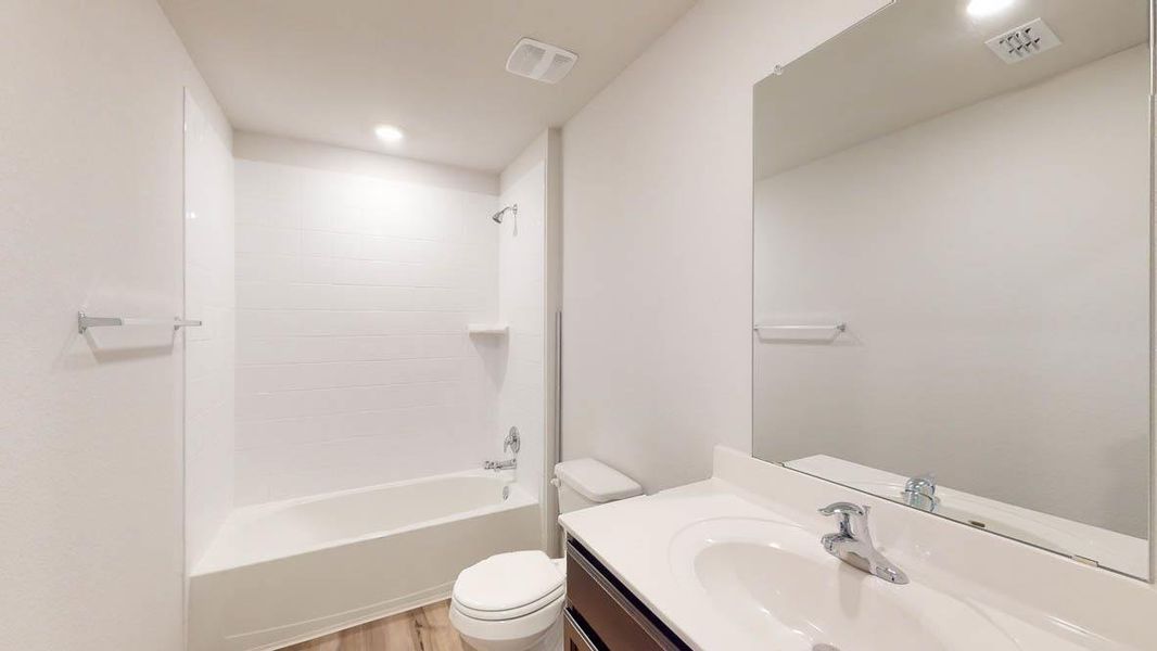 Bathroom featuring a white bathtub with tile surround, a built-in shelf, and a chrome shower fixture