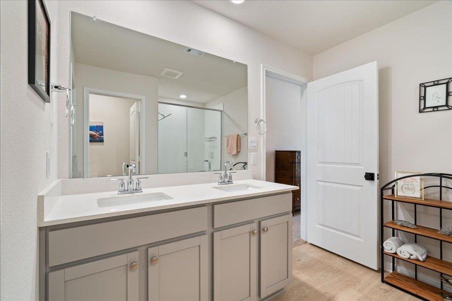 Bathroom featuring a stall shower, visible vents, wood finished floors, and a sink