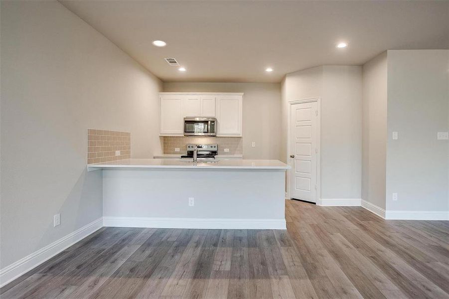 Kitchen with white cabinets, tasteful backsplash, appliances with stainless steel finishes, light wood-style floors, and recessed lighting Kitchen with white cabinets, tasteful backsplash, appliances with stainless steel finishes, light wood-style floors, and recessed lighting