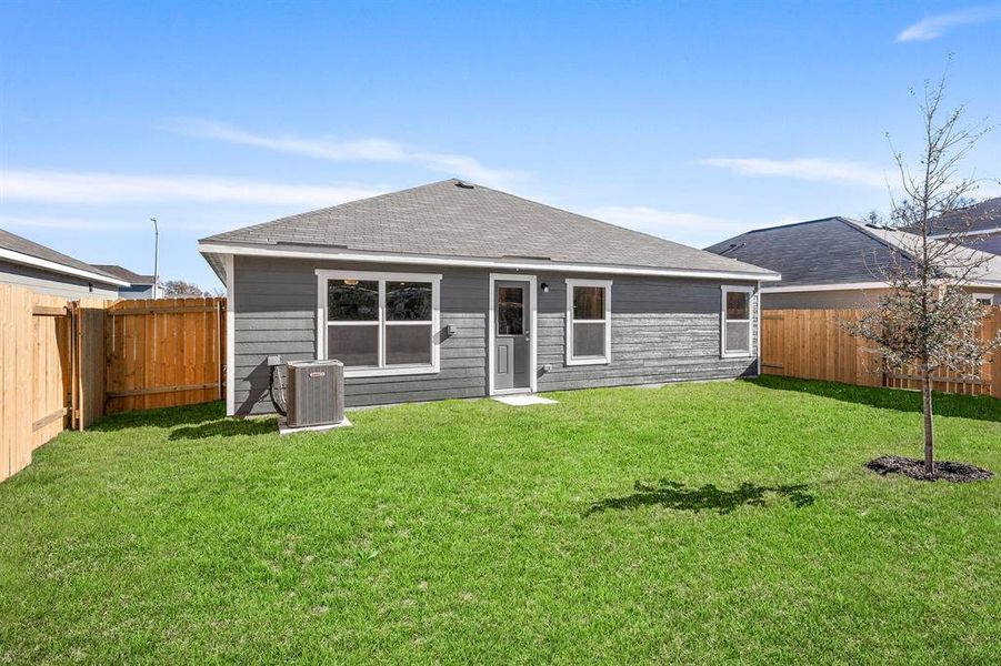 Rear view of property featuring central AC and a lawn