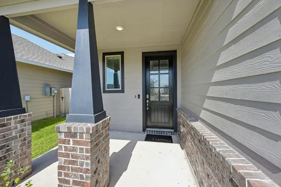 Charming front porch with rustic brick columns and a welcoming entrance featuring a stylish black door.