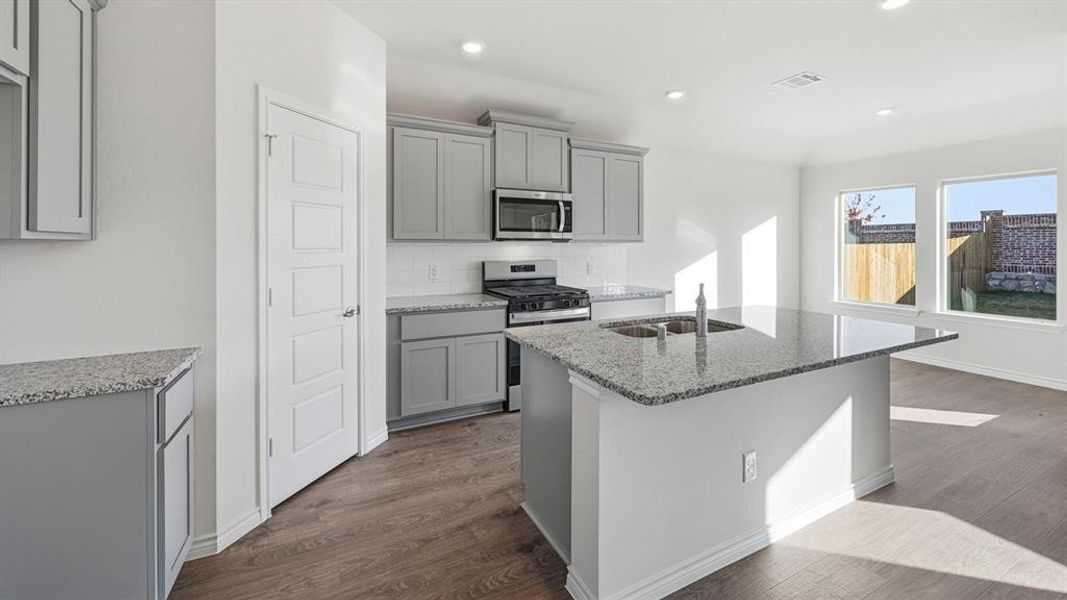 The kitchen features light grey cabinetry, granite countertops, and stainless steel appliances