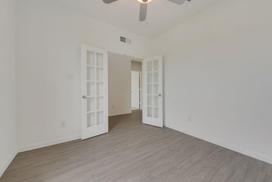 Spare room featuring french doors, light wood finished floors, and a ceiling fan Spare room featuring french doors, light wood finished floors, and a ceiling fan