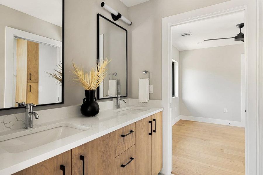 Bathroom with double vanity, light wood-type flooring, and ceiling fan