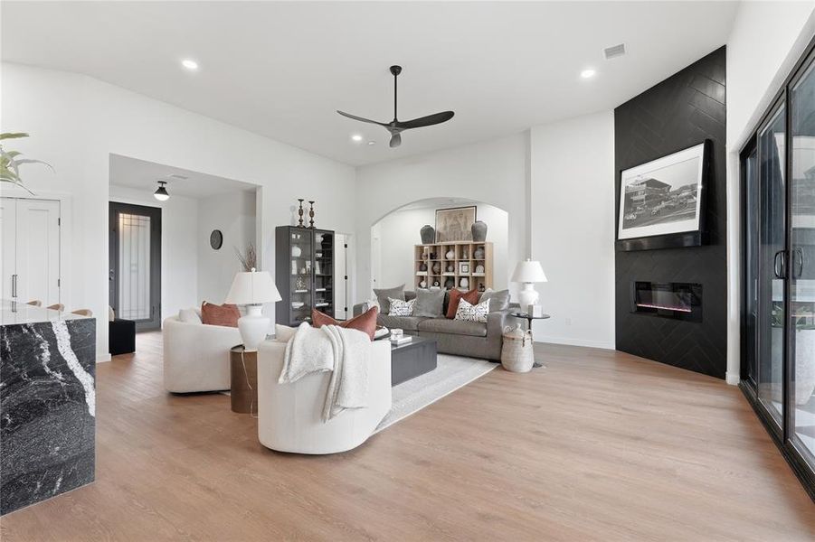 Spacious living area featuring light wood-finish flooring, a contemporary ceiling fan, and recessed lighting