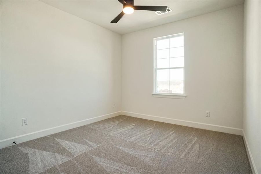 Carpeted empty room with baseboards and a ceiling fan