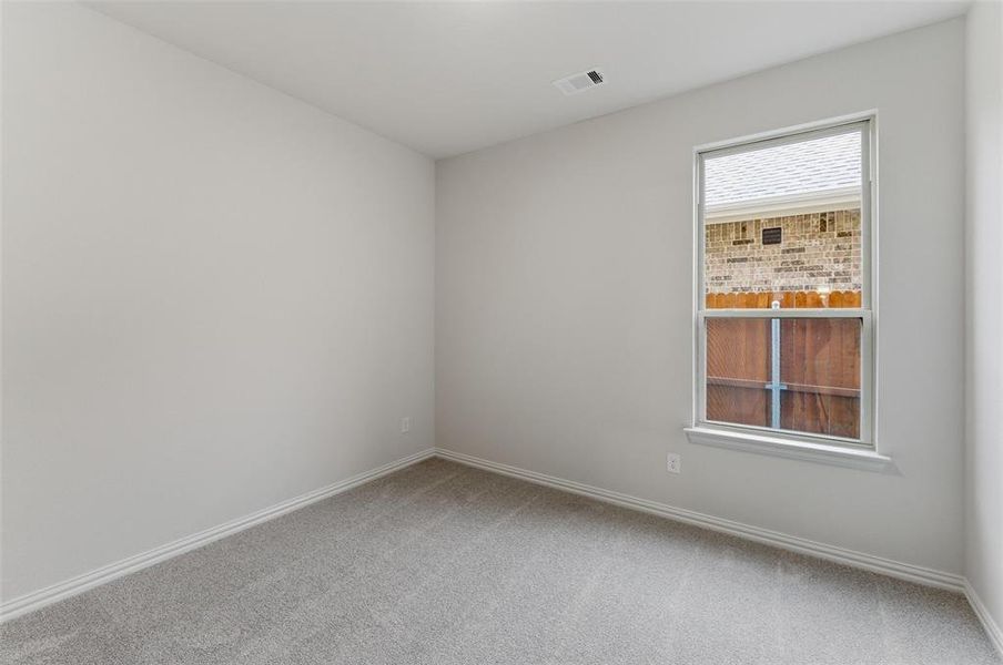 Neutral gray walls with white trim, gray carpet, and a single window featuring a white frame