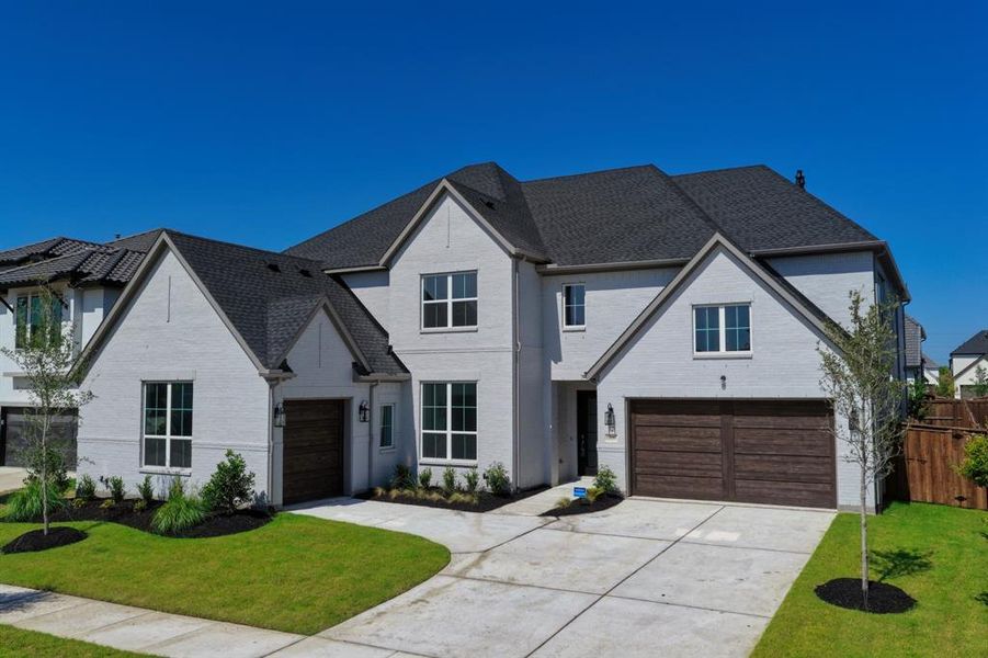 Two-story residence featuring a light-colored brick exterior, dark shingle roofing, and multiple gables Two-story residence featuring a light-colored brick exterior, dark shingle roofing, and multiple gables