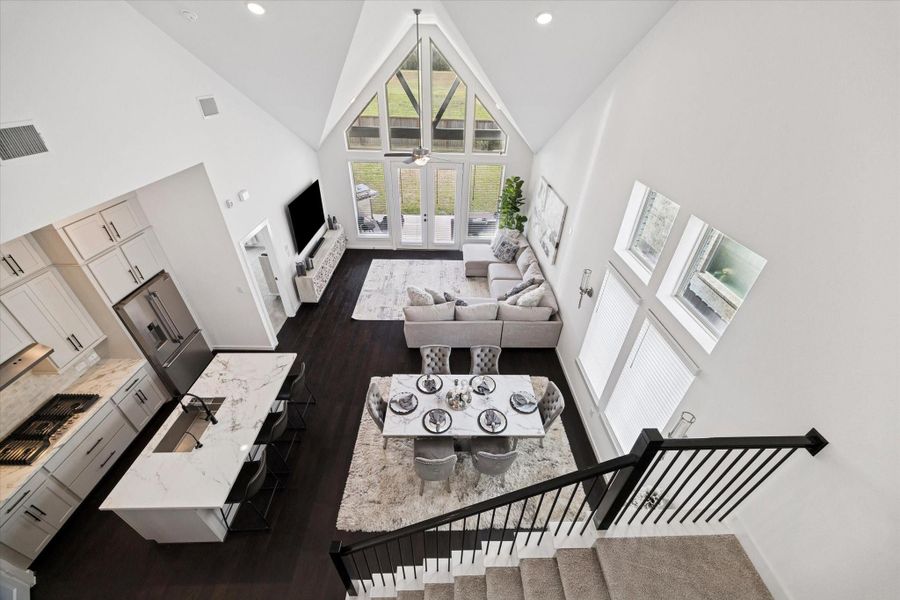 A VIEW FROM THE LANDING DISPLAYS THE EFFECIENT LAYOUT OF THE KITCHEN, DINING AREA, AND LIVING ROOM BENEATH THE VAULTED CEILING.