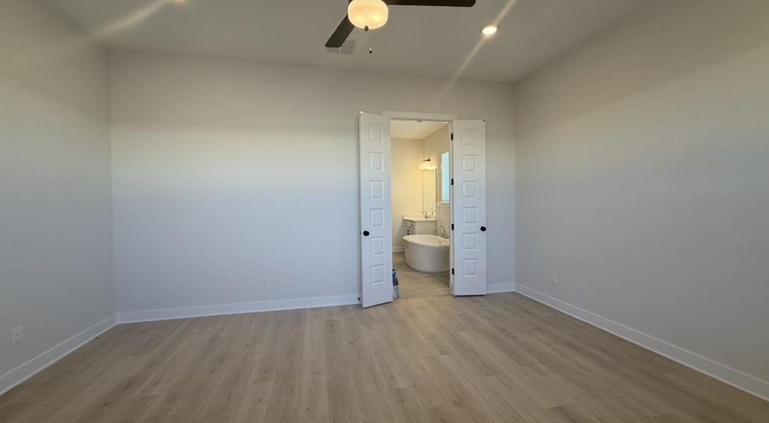 Unfurnished bedroom featuring light wood-style floors, a ceiling fan, ensuite bath, and recessed lighting