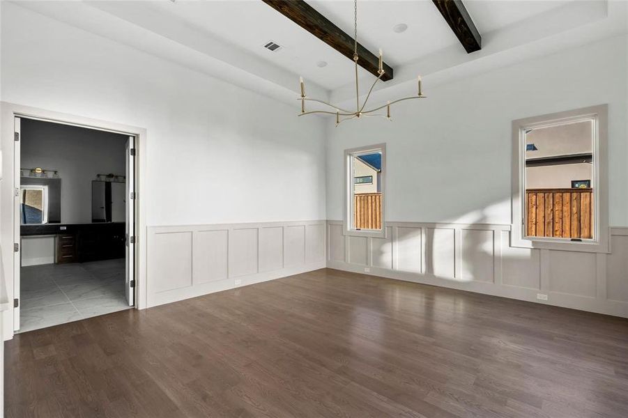 Spare room with dark wood-type flooring, beamed ceiling, a wainscoted wall, and a decorative wall Spare room with dark wood-type flooring, beamed ceiling, a wainscoted wall, and a decorative wall