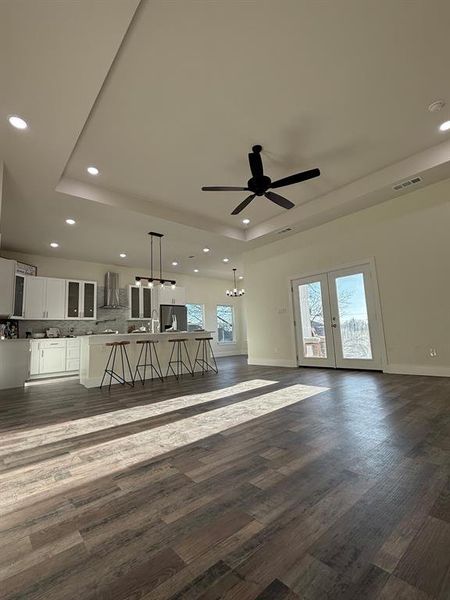Picture of open concept living room and kitchen together.  Double french doors leading out to covered back porch leading to swimming pool.
