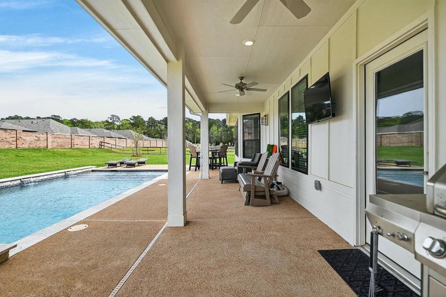 Extended covered patio with plenty of seating and mounted TV facing the pool & spa.
