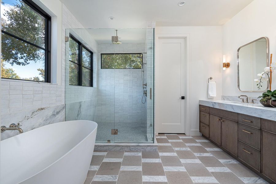 Polished nickel plumbing, brass lighting, classic zellige, deep stained white oak and a marble and limestone floor make the primary bathroom both calm and warm.