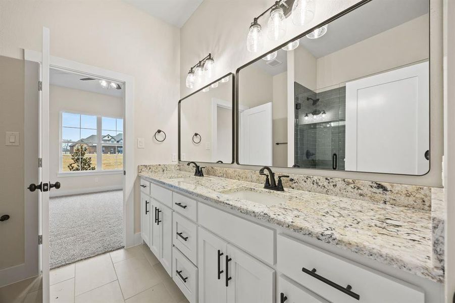 Full bath featuring double vanity, a shower stall, light colored carpet, and light tile patterned floors Full bath featuring double vanity, a shower stall, light colored carpet, and light tile patterned floors