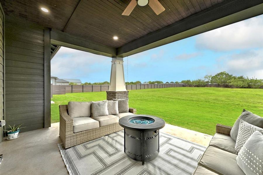 Fenced backyard with an outdoor living space with a fire pit, a patio area, and a ceiling fan