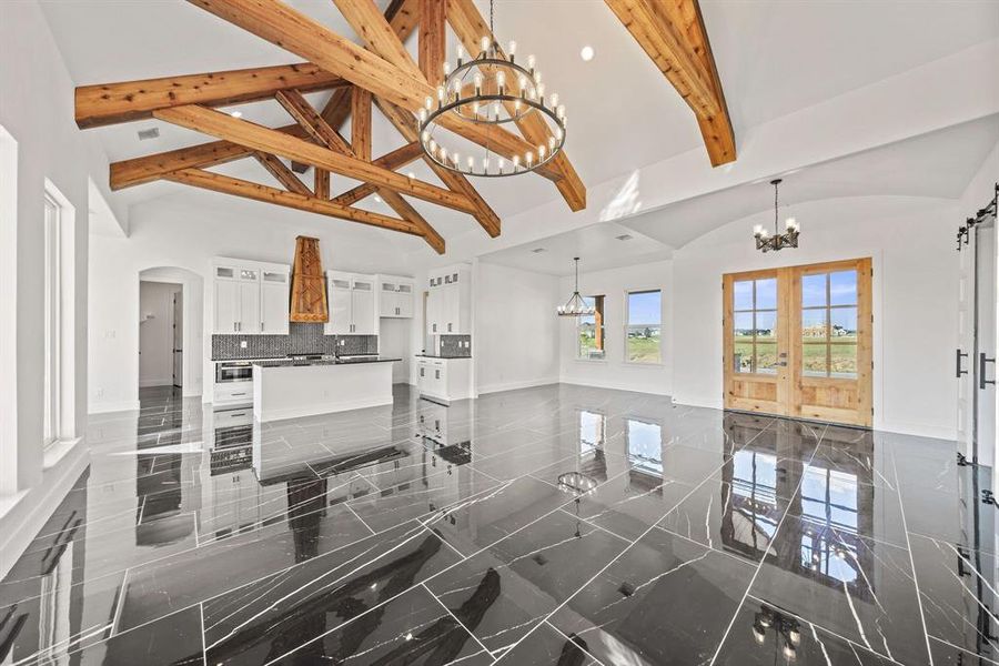 Living room featuring a chandelier, baseboards, high vaulted ceiling, arched walkways, and beam ceiling Living room featuring a chandelier, baseboards, high vaulted ceiling, arched walkways, and beam ceiling
