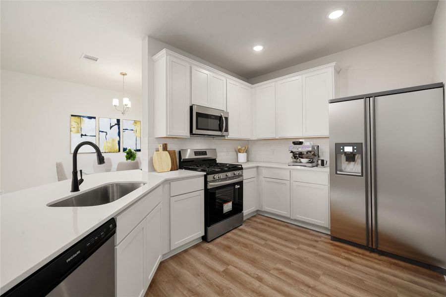 This beautifully designed kitchen showcases modern finishes and a functional layout. Bright white cabinetry and sleek countertops create a fresh, clean aesthetic, while stainless steel appliances add a contemporary touch. The open design provides seamless connection to the main living areas, making meal prep and everyday living effortless. Warm wood-style flooring enhances the inviting atmosphere, combining style and practicality in one elegant space. This beautifully designed kitchen showcases modern finishes and a functional layout. Bright white cabinetry and sleek countertops create a fresh, clean aesthetic, while stainless steel appliances add a contemporary touch. The open design provides seamless connection to the main living areas, making meal prep and everyday living effortless. Warm wood-style flooring enhances the inviting atmosphere, combining style and practicality in one elegant space.