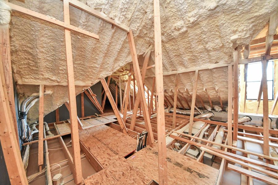 Spacious attic with exposed beams and spray foam insulation, ready for customization or ample storage.