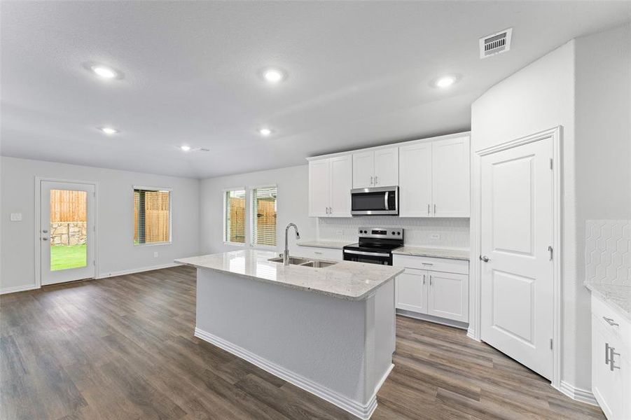 Kitchen with stainless steel appliances, dark wood finished floors, backsplash, light stone counters, and recessed lighting Kitchen with stainless steel appliances, dark wood finished floors, backsplash, light stone counters, and recessed lighting
