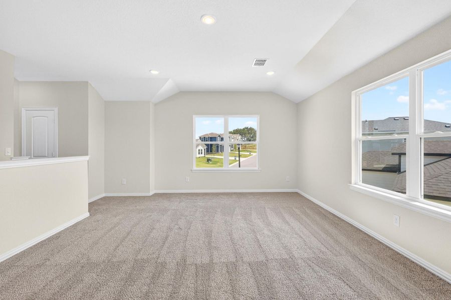 Plentiful windows fill this carpeted upstairs living space with natural light.