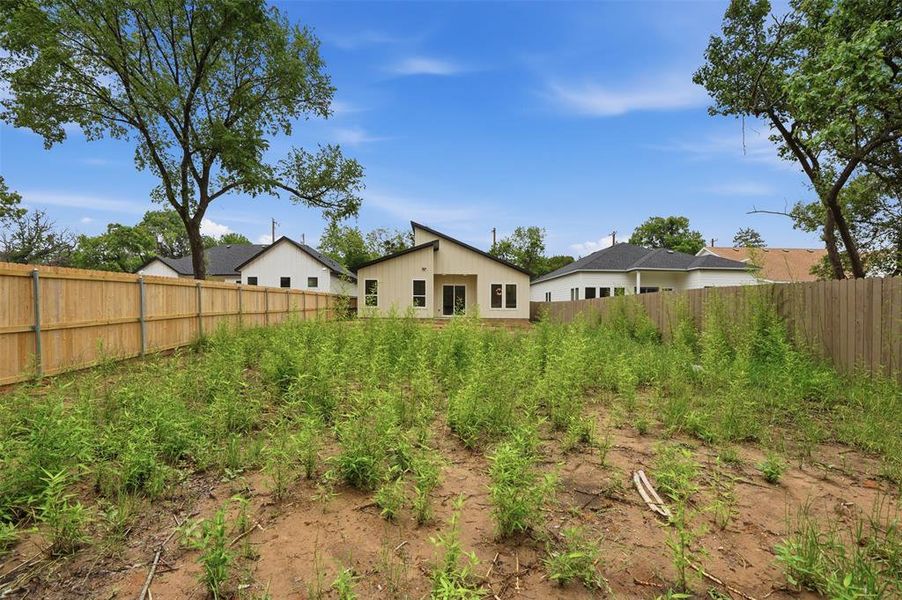 Spacious backyard featuring a new wood fence and mature trees