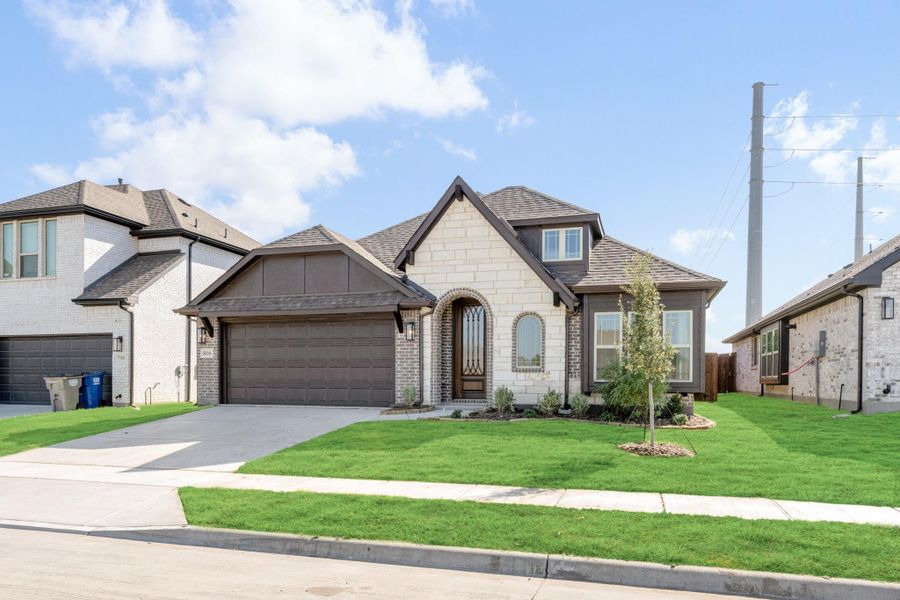 Single-story home with stone and brick exterior, two-car garage, and manicured front lawn
