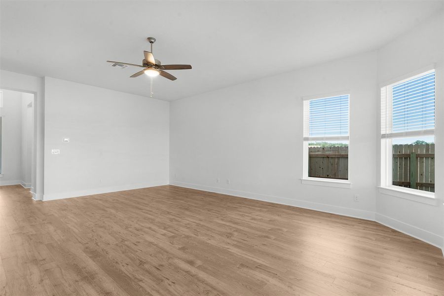 A spacious room offers comfortable living with warm wood flooring and ample natural light.